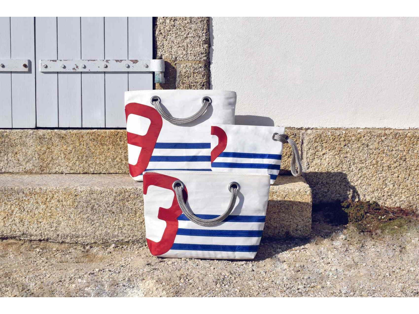 With its blue stripes and red number, this chic and practical tote bag has been sewn by hand from recycled sails and has been designed for lovers of all things nautical and French with a strong sense of style. 